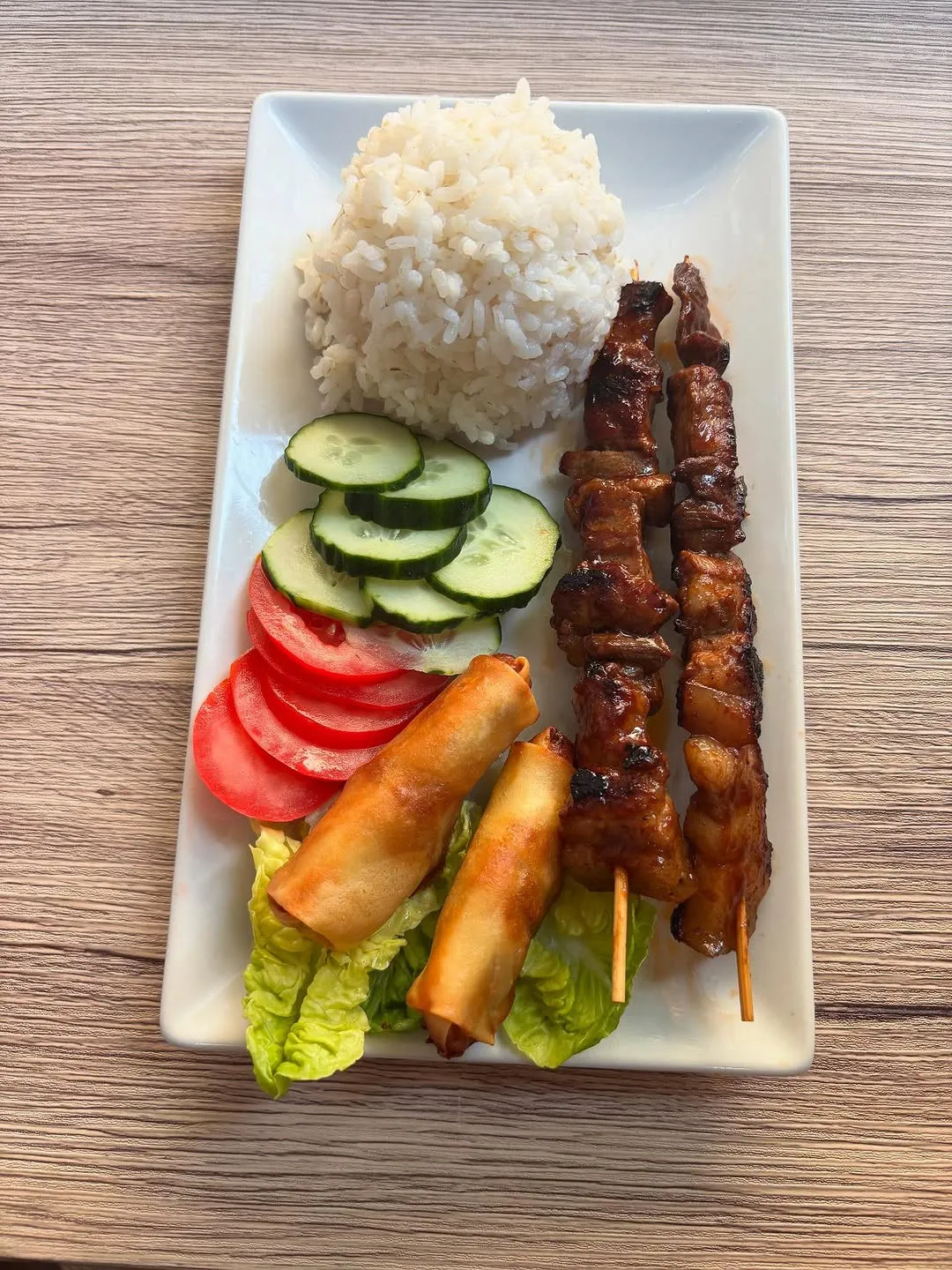 Plato combinado filipino con brocheta bbq, rollito shanghai, arroz, pepino y tomate
