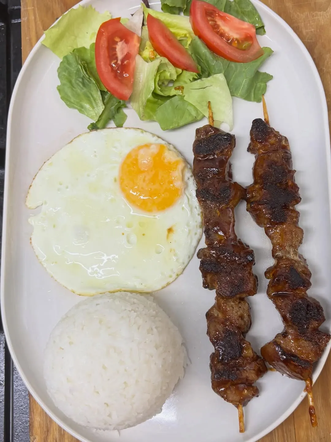 Barsilog: dos brochetas bbq, huevo frito, arroz y ensalada